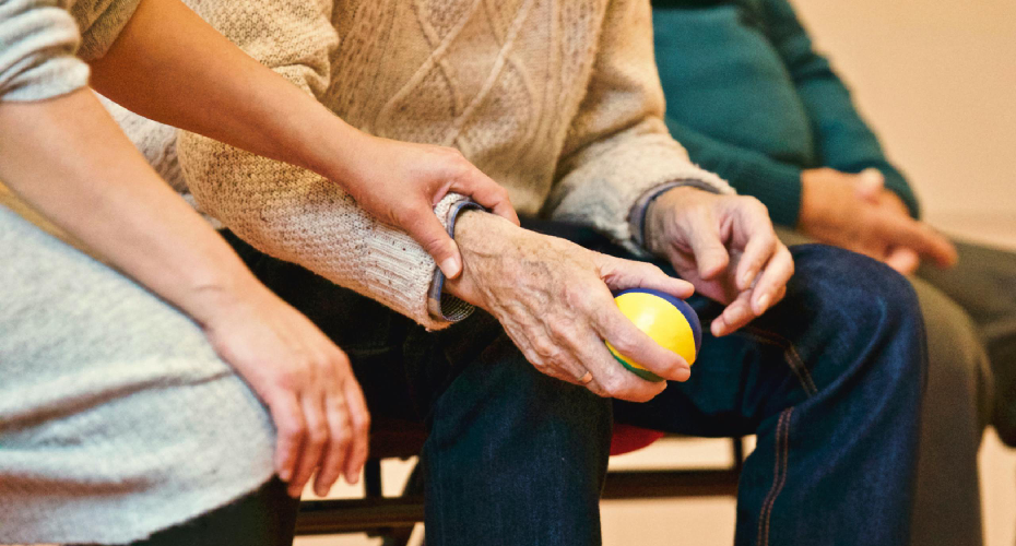 Care giver's hand holding an elderly person wrist.